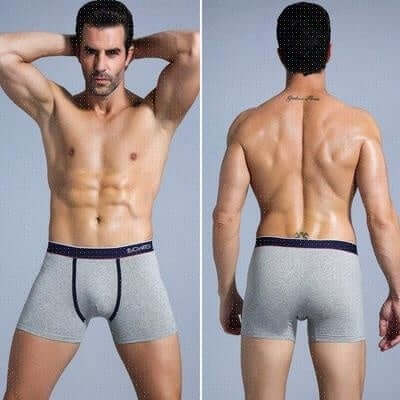 Front and back view of a fit male model wearing gray cotton boxer briefs with contrasting navy waistband, showcasing design and fit.