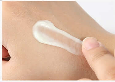 Finger applying a streak of moisturizing lanolin cream on skin to demonstrate the texture and efficacy of the skincare product.