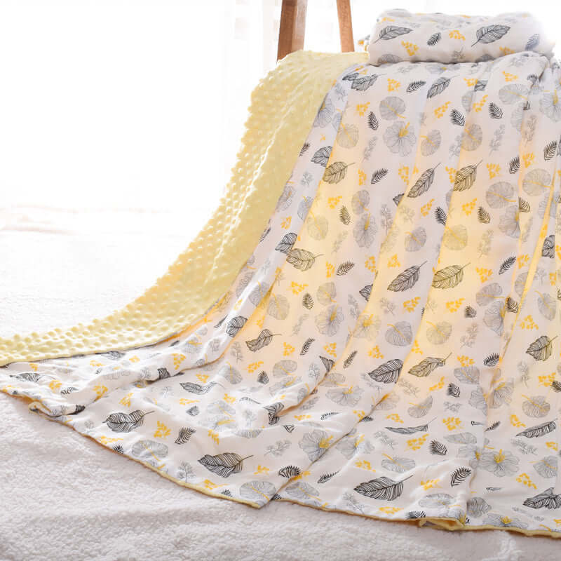 Baby Doudou blanket with 3D hot-pressed bubble design, featuring yellow and gray nature-themed patterns, draped over a chair.