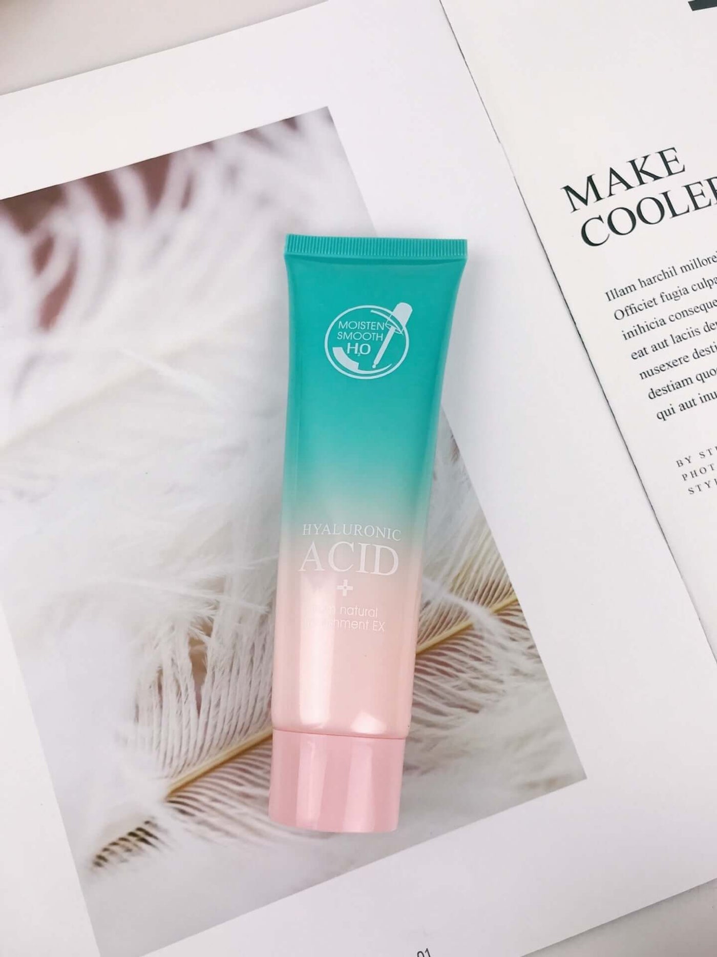 Hyaluronic acid moisturizing facial cream tube on a magazine page with feathers in the background