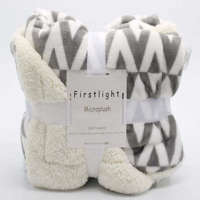 Rolled polyester lambskin-style blanket with geometric gray and white pattern, labeled "Firstlight Microplush"