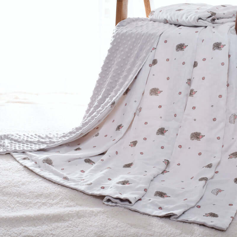 Baby Doudou blanket with 3D bubble design draped over chair, featuring hedgehog patterns for sensory development.