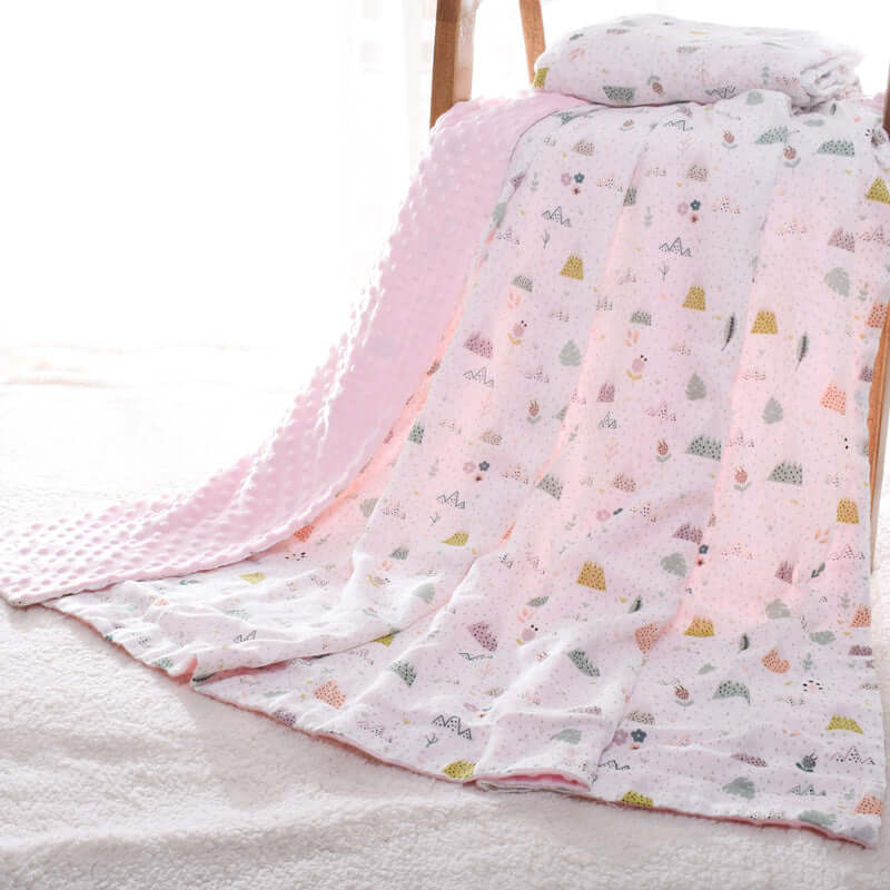 Baby blanket Doudou with 3D bubble design draped over a chair, featuring pastel tones and patterns for sensory stimulation.