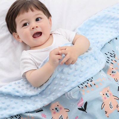 Happy baby lying on a blue 3D Doudou blanket with animal patterns, promoting sensory development