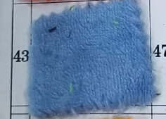 Close-up of a blue flannel fabric sample for pet blankets on a measured grid background