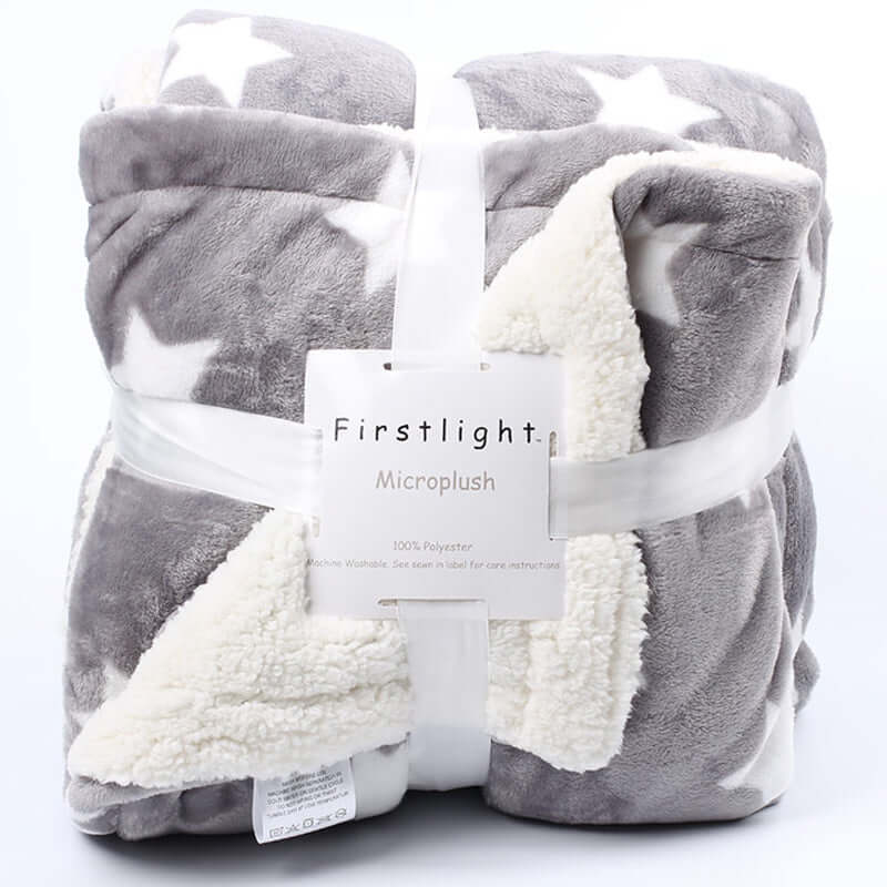 Folded gray and white star-patterned microplush blanket with faux lambskin lining and product label visible