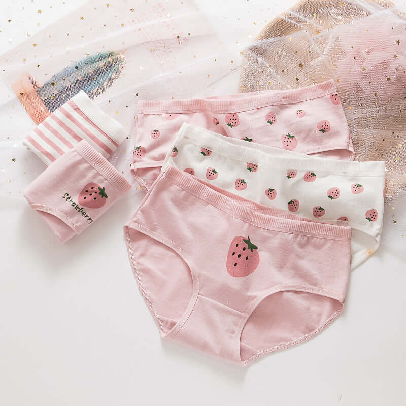 Pack of five girls' cotton cute underwear in lotus root powder color with strawberry prints, displayed alongside a decorative mesh fabric.