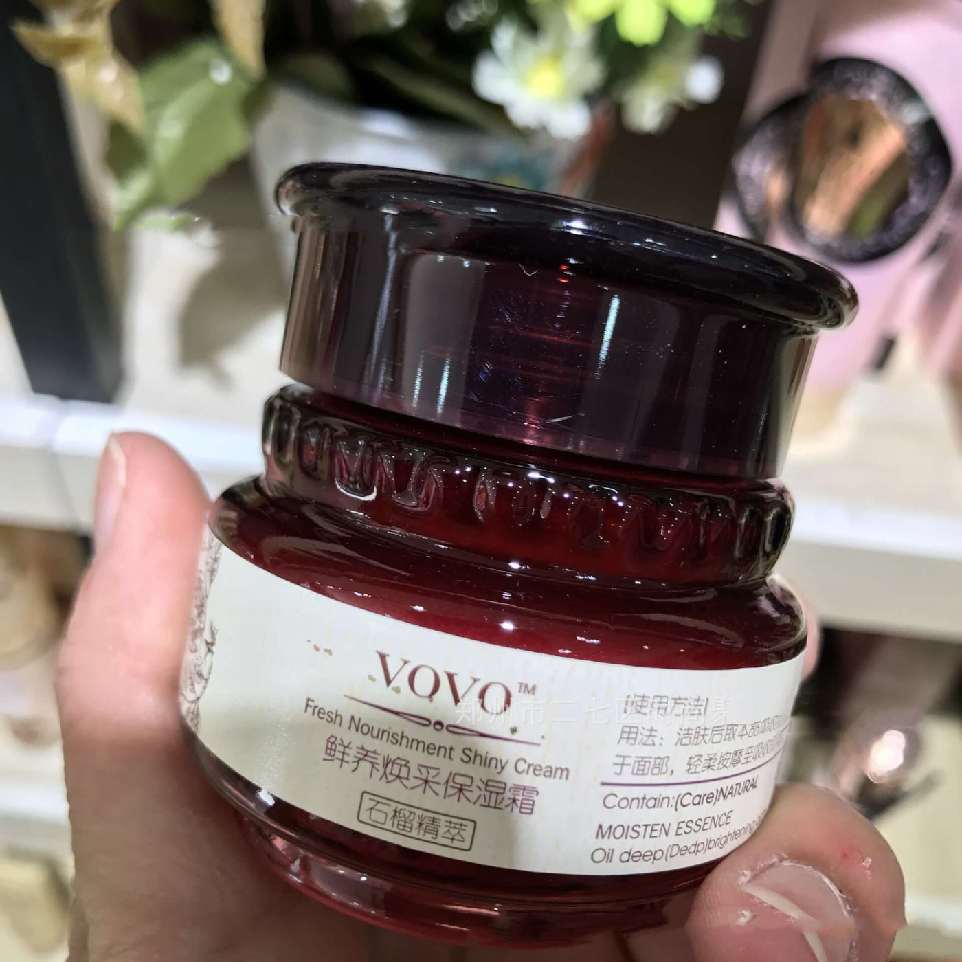 Hand holding a jar of VOVÓ Fresh Nourishment Shiny Cream in a store setting