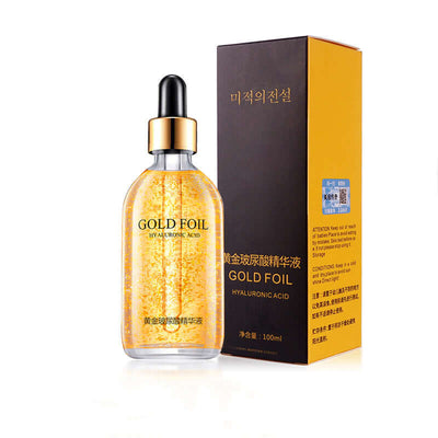 Bottle of gold foil hydrating skin care essence with dropper next to its black and gold packaging box, showcasing moisturizing and firming benefits.